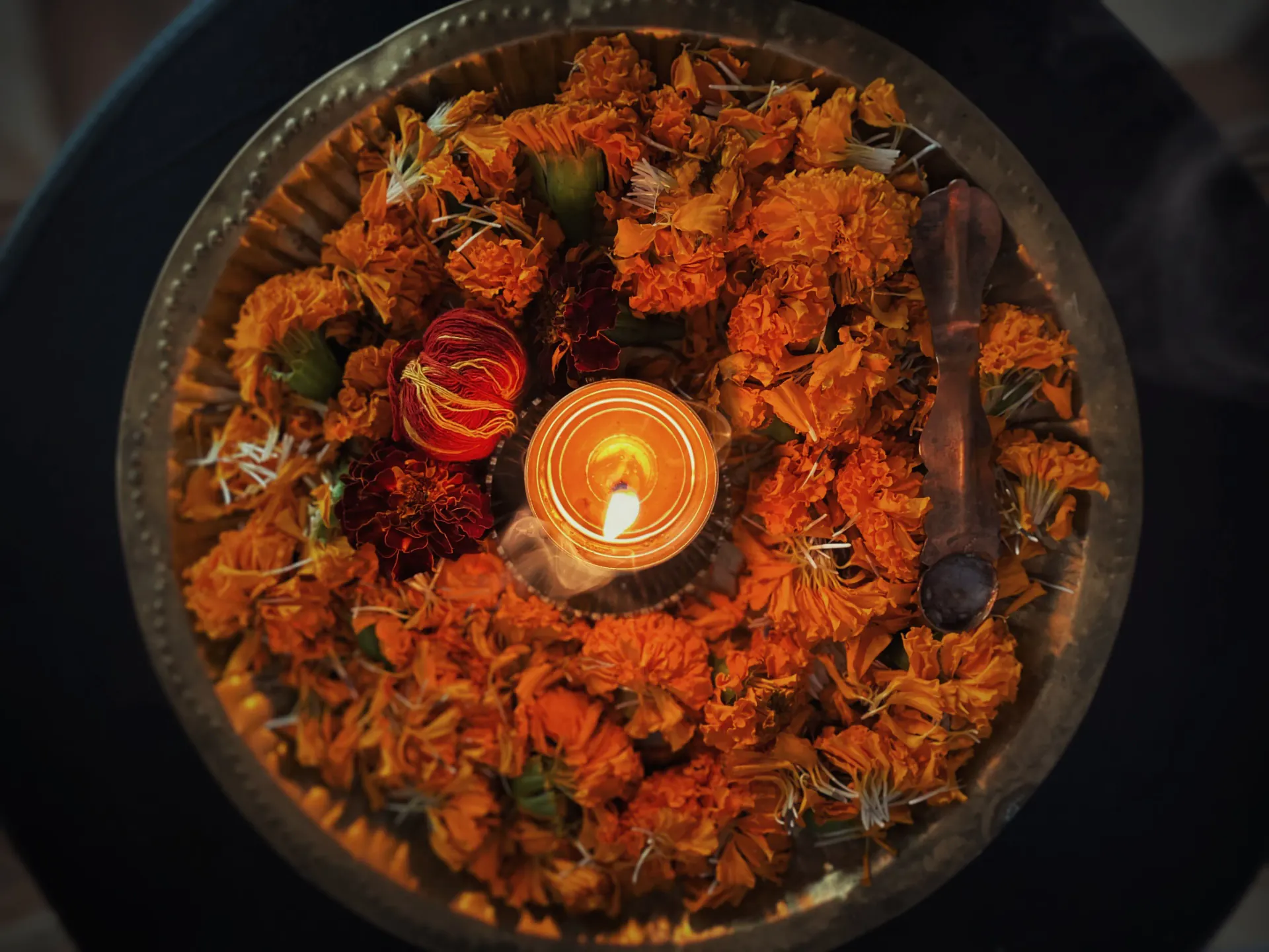 Marigold flower offering with a lit diya lamp for a traditional puja