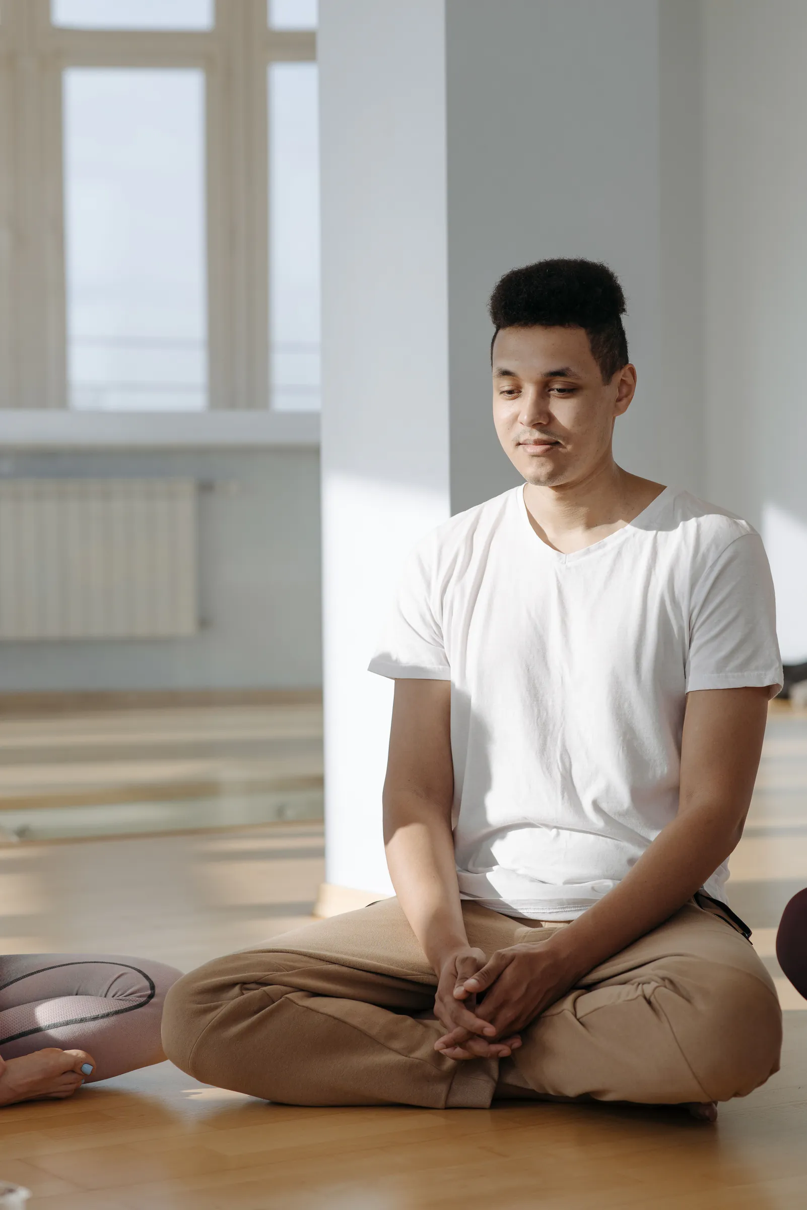 Young man sitting on the floor practising calm, mindful meditation