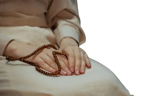 Hands resting on the lap holding a wooden prayer mala