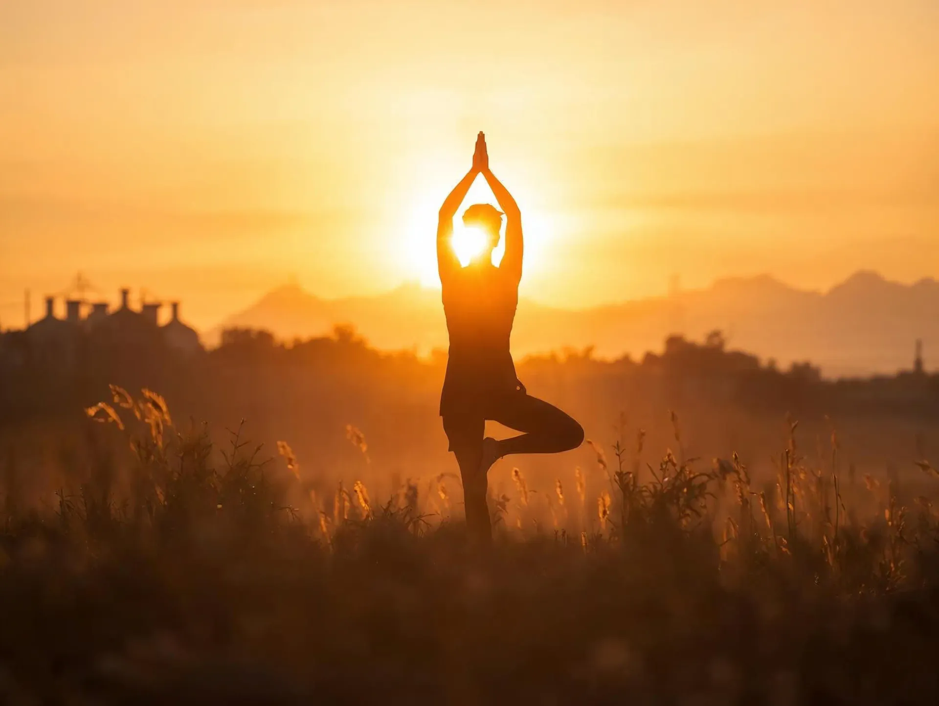 Silhouette of a person in yoga tree pose at sunset
