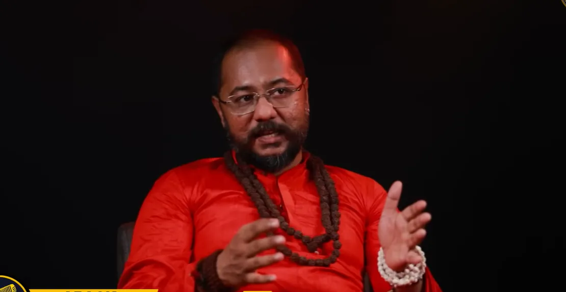 Swami Bhadraanand in a red kurta during a studio video interview