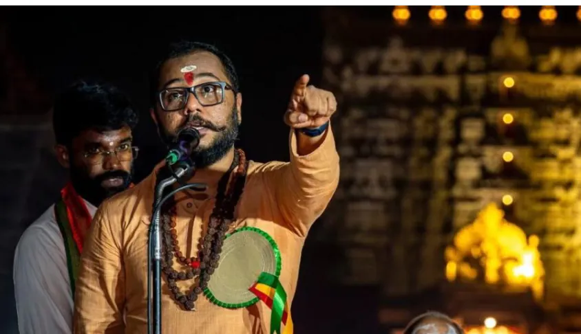 Swami Bhadraanand pointing towards a temple gathering at night
